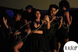 Alunos vestidos de preto se entrelaçam em uma corda durante apresentação artística