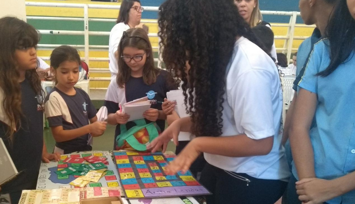 Uma adolescente negra apresenta um jogo de tabuleiro para crianças menores