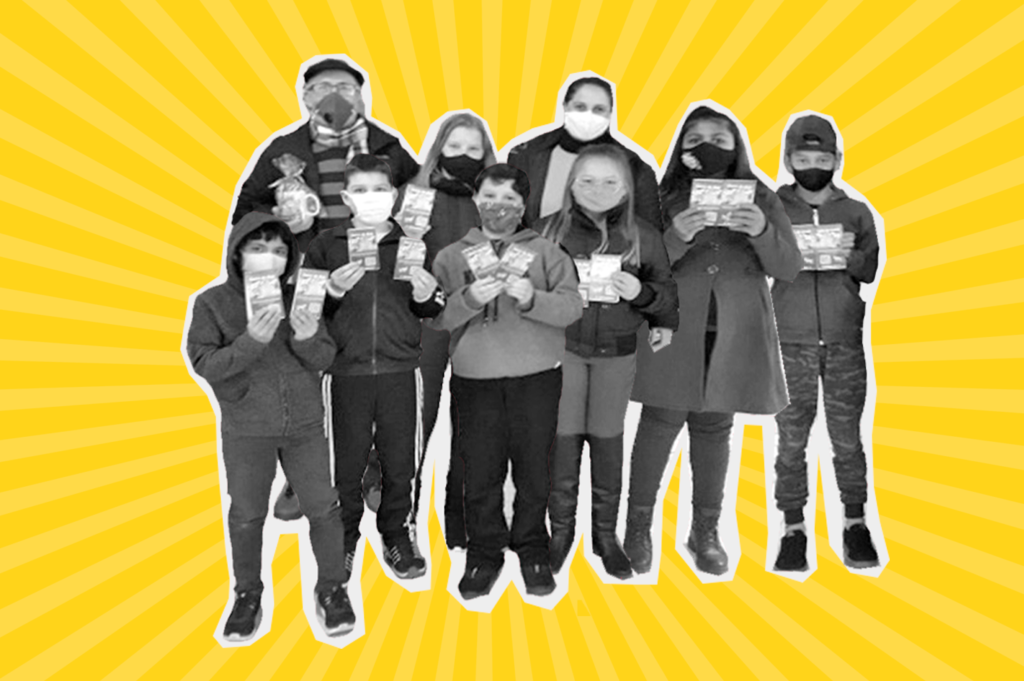 Arte com fundo amarelo e foto de um grupos de 9 pessoas, sendo 7 crianças brancas e dois adultos brancos. Todos seguram papeis e usam máscara de proteção.